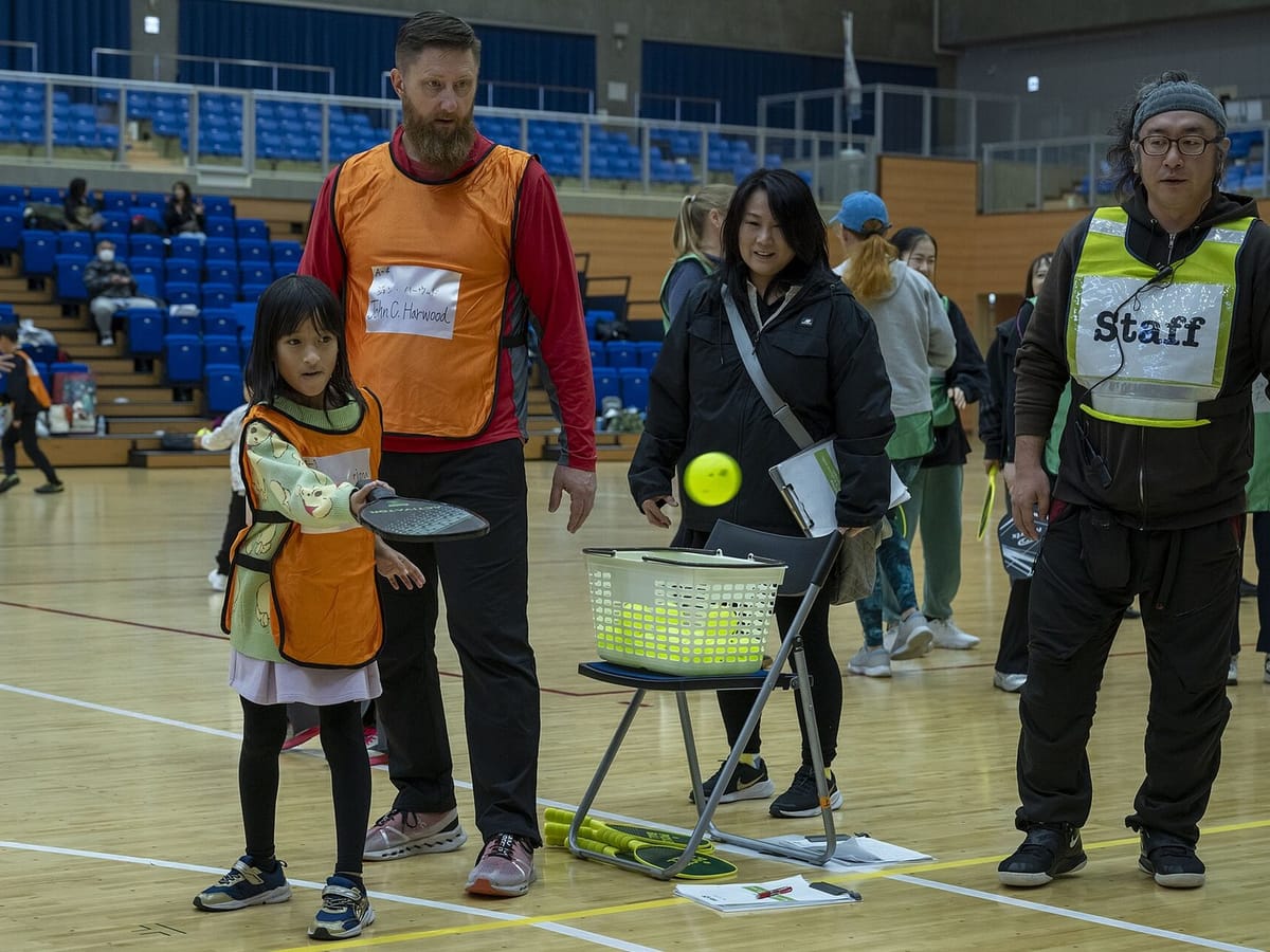 A child holding a pickleball paddle on a court