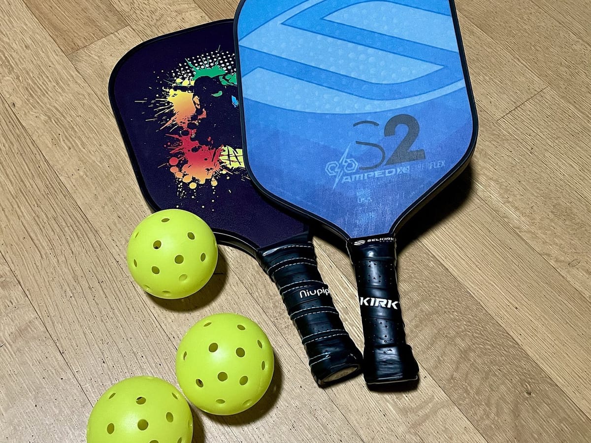 A pickleball paddle and ball on a court
